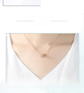 Close-up of rose gold interlocking double heart necklace with crystal inlay on model