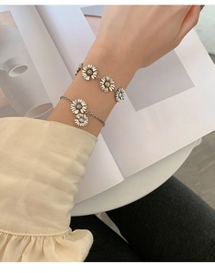 Detailed view of s925 silver daisy bracelets worn on wrist with floral metal texture
