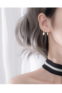 Close-up of 925 sterling silver hoop earrings with star and cross charms on a model