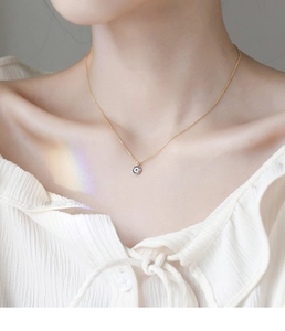 Close-up of S925 silver evil eye pendant necklace worn by model on collarbone