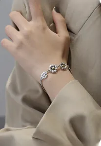 Close-up of vintage S925 silver daisy bracelet with gold accents on model wrist