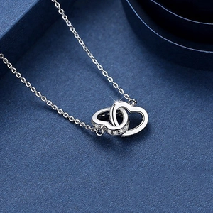 Silver interlocking heart necklace with pavé crystals on a luxury blue gift box