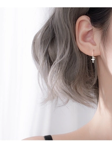 Detailed close-up of a minimalist 925 sterling silver cross charm hoop earring on model