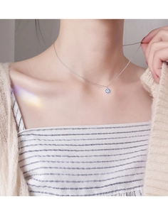 Detailed close-up of a s925 silver evil eye necklace worn by a model on a beige sweater