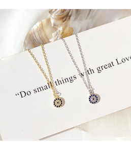 Detail of silver and gold evil eye necklaces with blue crystals on natural stone background