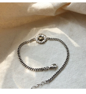 Detail view of S925 vintage silver daisy bracelet with golden center on linen fabric