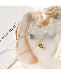 Macro shot of silver and gold evil eye necklaces with blue cubic zirconia in a shell