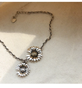 Close-up of vintage daisy pendants with golden heart and small heart tag on silver chain