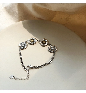 Detailed close-up of s925 silver daisy bracelet with golden stamen on a tray