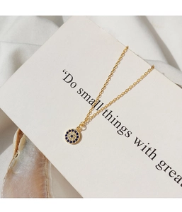 Detail of s925 silver evil eye pendant with blue gemstones on a gold necklace chain