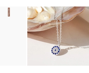 Macro shot of S925 silver Evil Eye necklace with blue zircon on a pearl shell