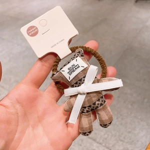 Détail d'élastique ours en peluche avec motif léopard brun et nœud en ruban blanc