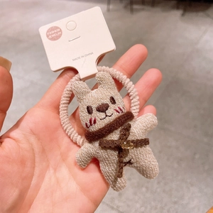 Détail de l'élastique à cheveux lapin tricoté beige avec écharpe brune et bande spirale