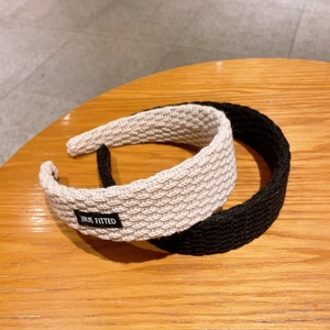 Detailed close-up of knitted texture and logo label on wide-brimmed hairbands