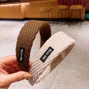 Detailed texture of knitted headbands in brown and beige with woven brand labels