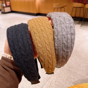 Detailed macro view of cable knit headbands in black, mustard yellow, and charcoal grey
