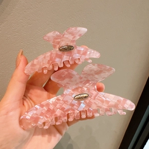 Close-up of pink checkered hair claws with Love is Forever metal plaques in two sizes