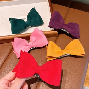 Detailed view of handmade woolen bow hair clips in vibrant colors with metal duckbill clips
