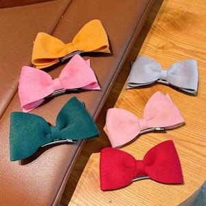 Set of six colorful wool bow hair clips on leather and wood display for girls
