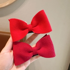 Close-up of wool bow hair clips in vibrant red and wine red with thick textured fabric
