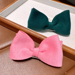 Close-up of pink and dark green velvet bow hair clips on a wooden display tray