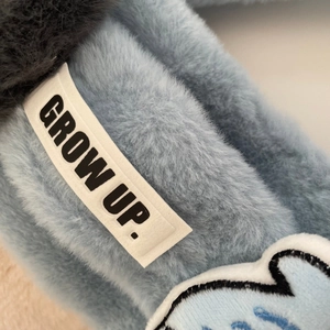 Dettaglio di sciarpa blu in peluche con etichetta in tessuto e ricamo morbido