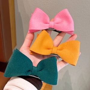 Three wool felt bow hair clips in pink, yellow, and green colors with duckbill clips