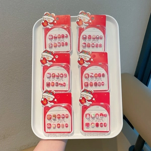 Primer plano de uñas postizas rojas para niñas con motivos de león de Año Nuevo