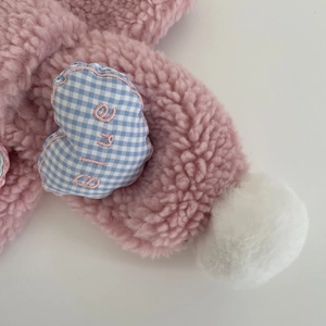 Détail de l'écharpe en polaire rose avec patch cœur à carreaux bleus et pompon blanc doux