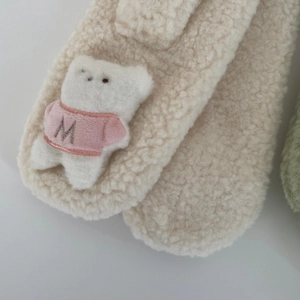 Détail d'une écharpe en polaire crème avec un ours en peluche 3D avec un pull rose et lettre M