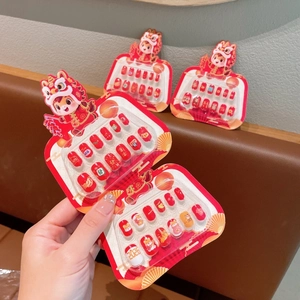 Close-up of festive red press-on nails featuring cute cartoon lion and koi fish designs
