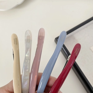 Dettaglio di cinque fermagli per capelli in acetato con scritte dorate fatte a mano