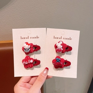 Detailed view of red hair clips featuring Hello Kitty, rabbit, and cherry designs