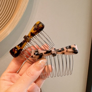 Detailed view of handmade acetate bow hair combs with tortoiseshell patterns and metal teeth