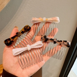 Bow-shaped acetate hair combs in tortoiseshell and marble patterns with metal teeth