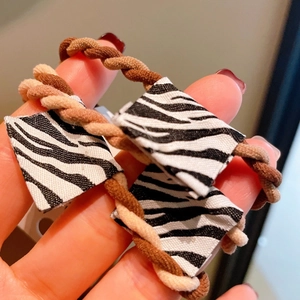 Detail of woven spiral hair ties in brown and apricot with zebra pattern accent