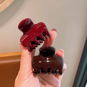 Close-up of glossy burgundy and dark brown acrylic hair claws with a polished finish