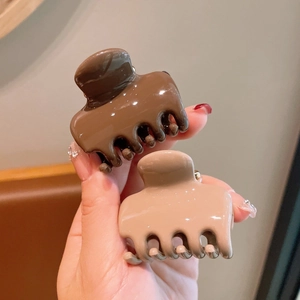 Close-up of brown and beige high-gloss acrylic hair claws with a polished mirror finish