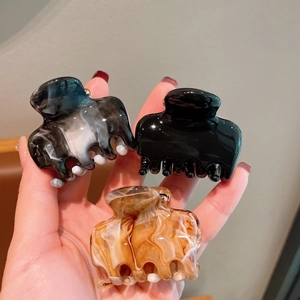 Detailed view of glossy amber, smoke grey, and black acrylic mini hair claw clips