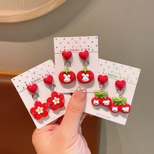 Detailed view of three pairs of red cartoon clip-on earrings for kids with heart bases