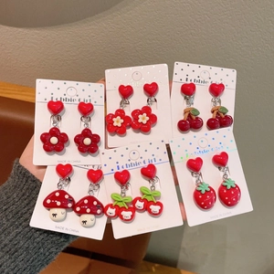 Close-up of red heart clip-on earrings with cute cherry and flower charms for girls