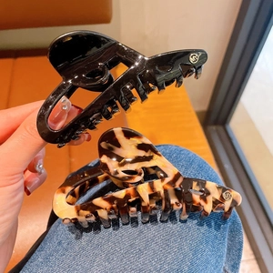 Set of large black and tortoiseshell hair claws with metal logo on a lifestyle background