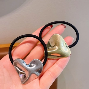 Dettaglio di elastici per capelli con ciondoli a cuore in metallo lucido oro e argento