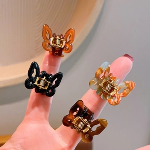 Macro shot of four colorful mini acetate butterfly hair clips on fingers showing small size