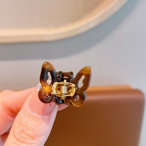 Close-up of tortoise shell butterfly hair claw clip with golden metal spring detail