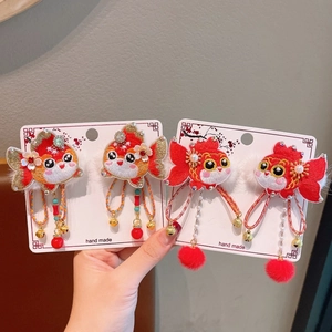 Close-up of handmade embroidered goldfish hair clips with bells and tassels for girls