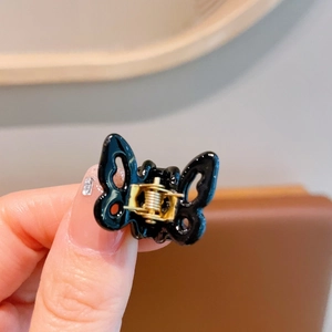 Close-up of a mini black acetate butterfly hair claw clip held by hand showing fine detail