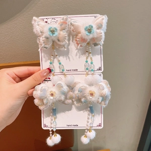 Close-up of handmade butterfly hair clips with pink fabric flowers and white pom-poms
