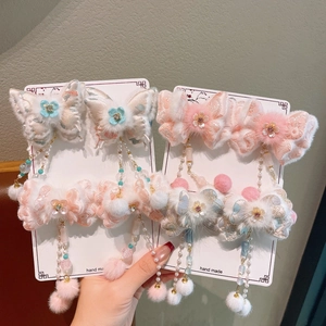 Detailed view of handmade butterfly hair clips with plush pom-poms and pearl tassels