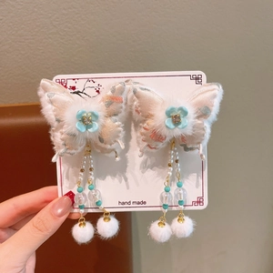 Detail of butterfly hair clips with pink embroidery, soft fur edges and long bead tassels